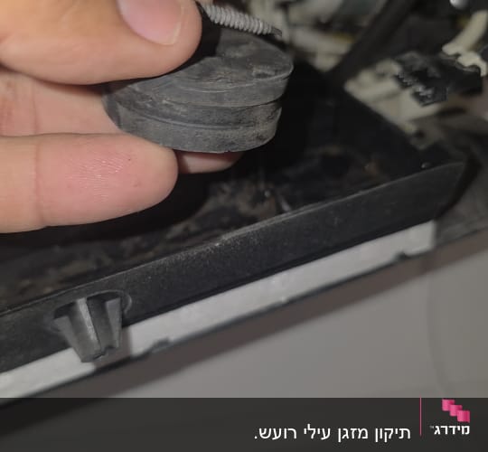 יד מחזיקה חלק ממזגן עם צינורות